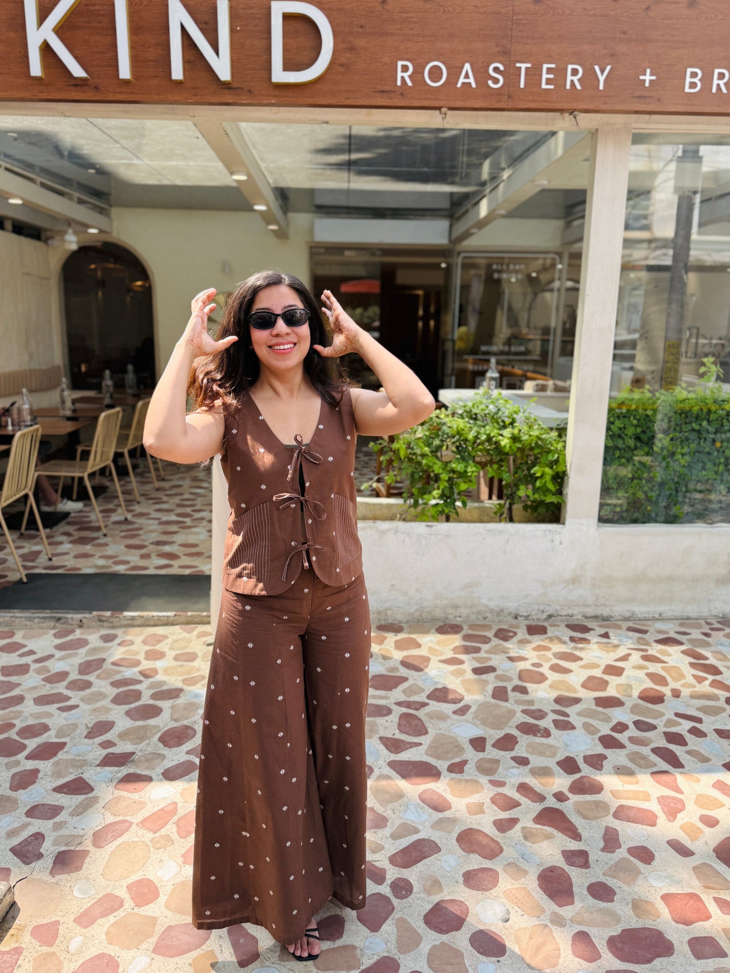 Woman posing in front of 'The Pizza Bar' with 'Kind Roastery & Brea' sign.