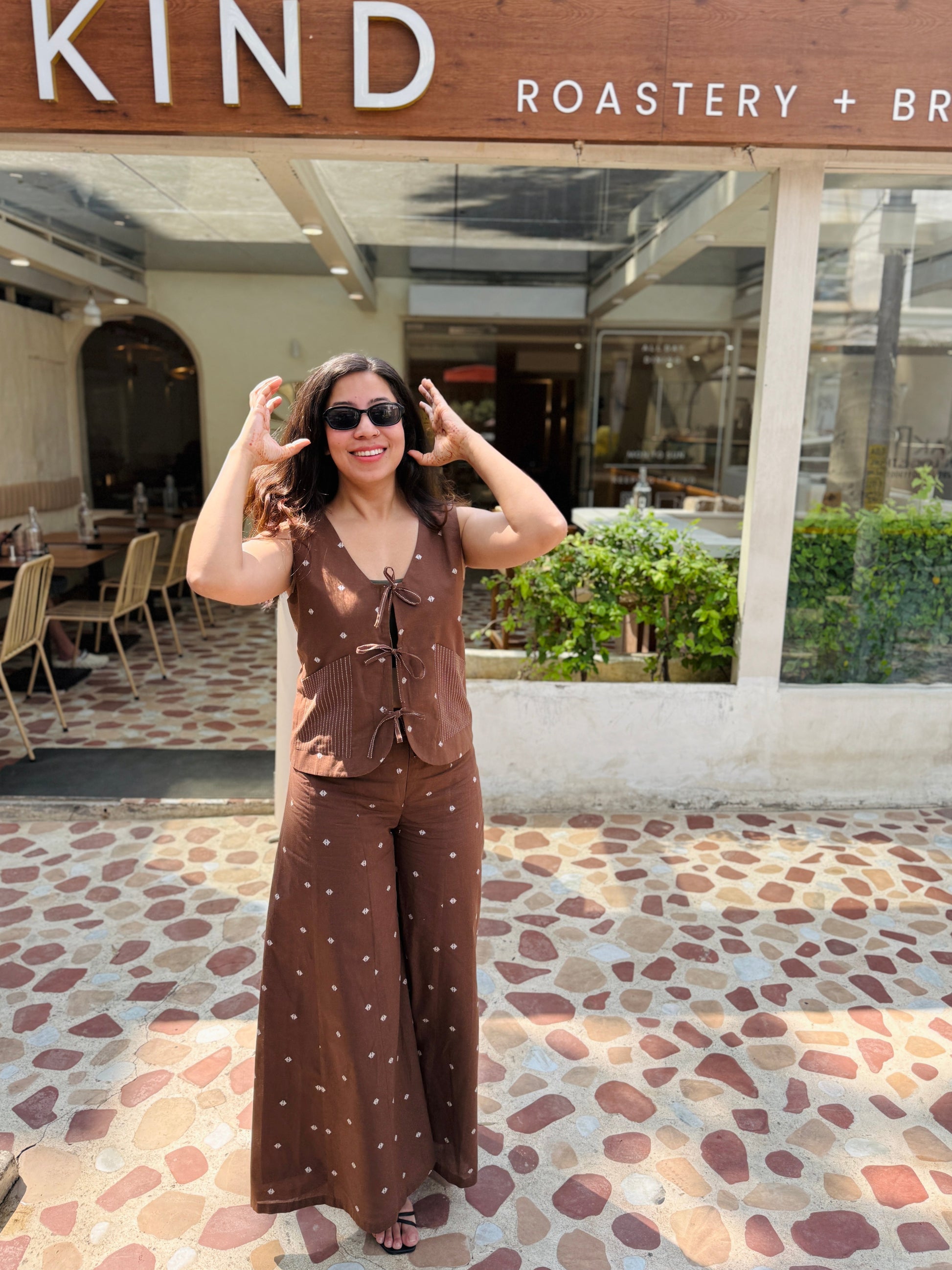 Woman posing in front of 'The Pizza Bar' with 'Kind Roastery & Brea' sign.