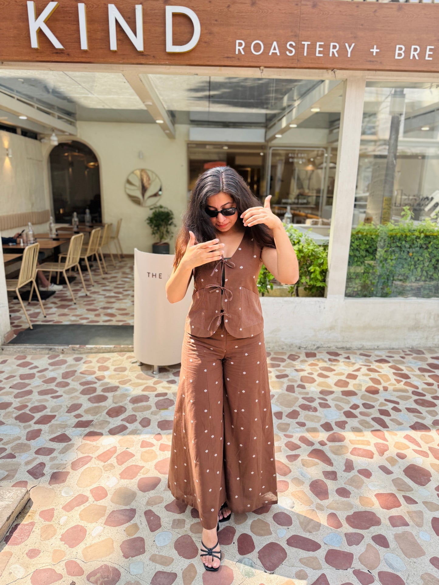 Woman taking a selfie in front of 'KIND Roastery & Brew' with a polka dot outfit.