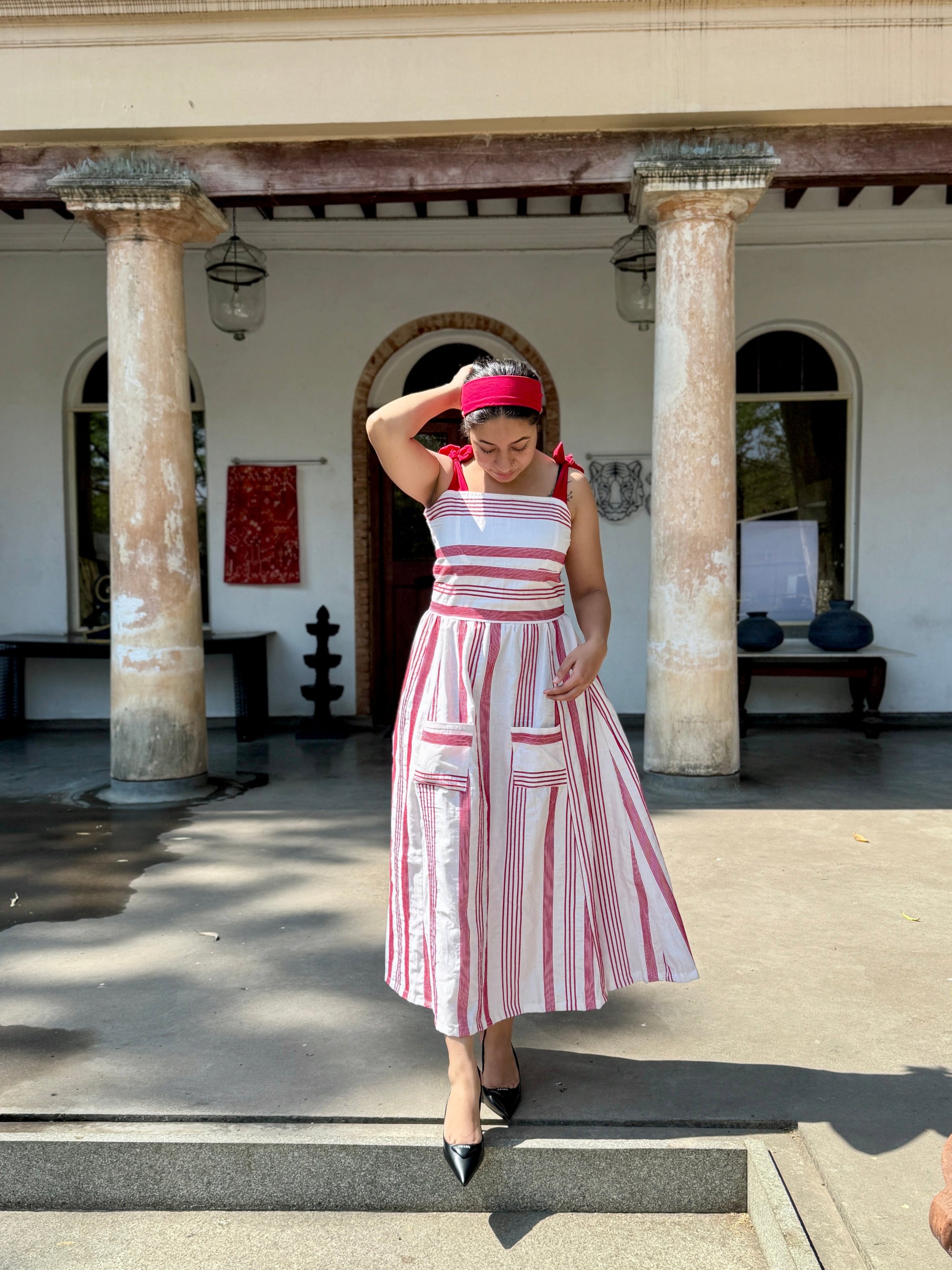 Woman in a red and white striped dress posing in front of a building with 'CINNAMON' on the wall.