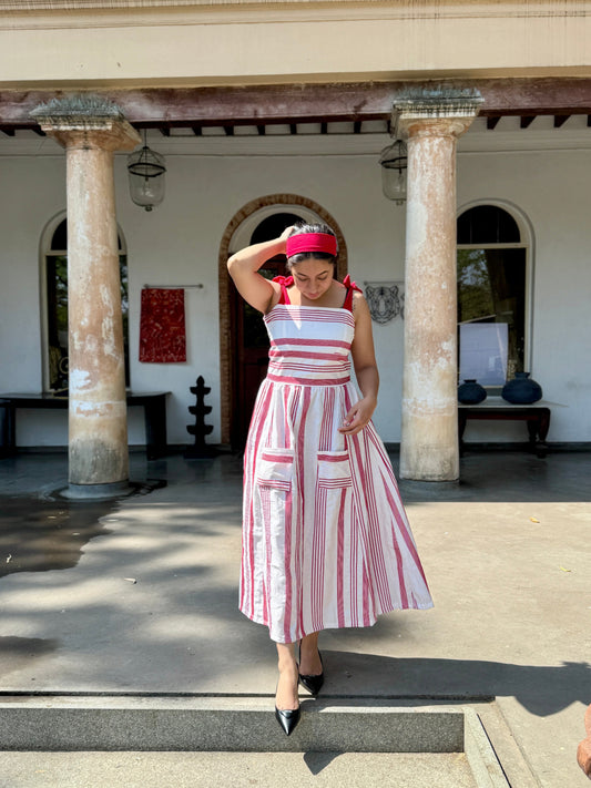 Woman in a red and white striped dress posing in front of a building with 'CINNAMON' on the wall.