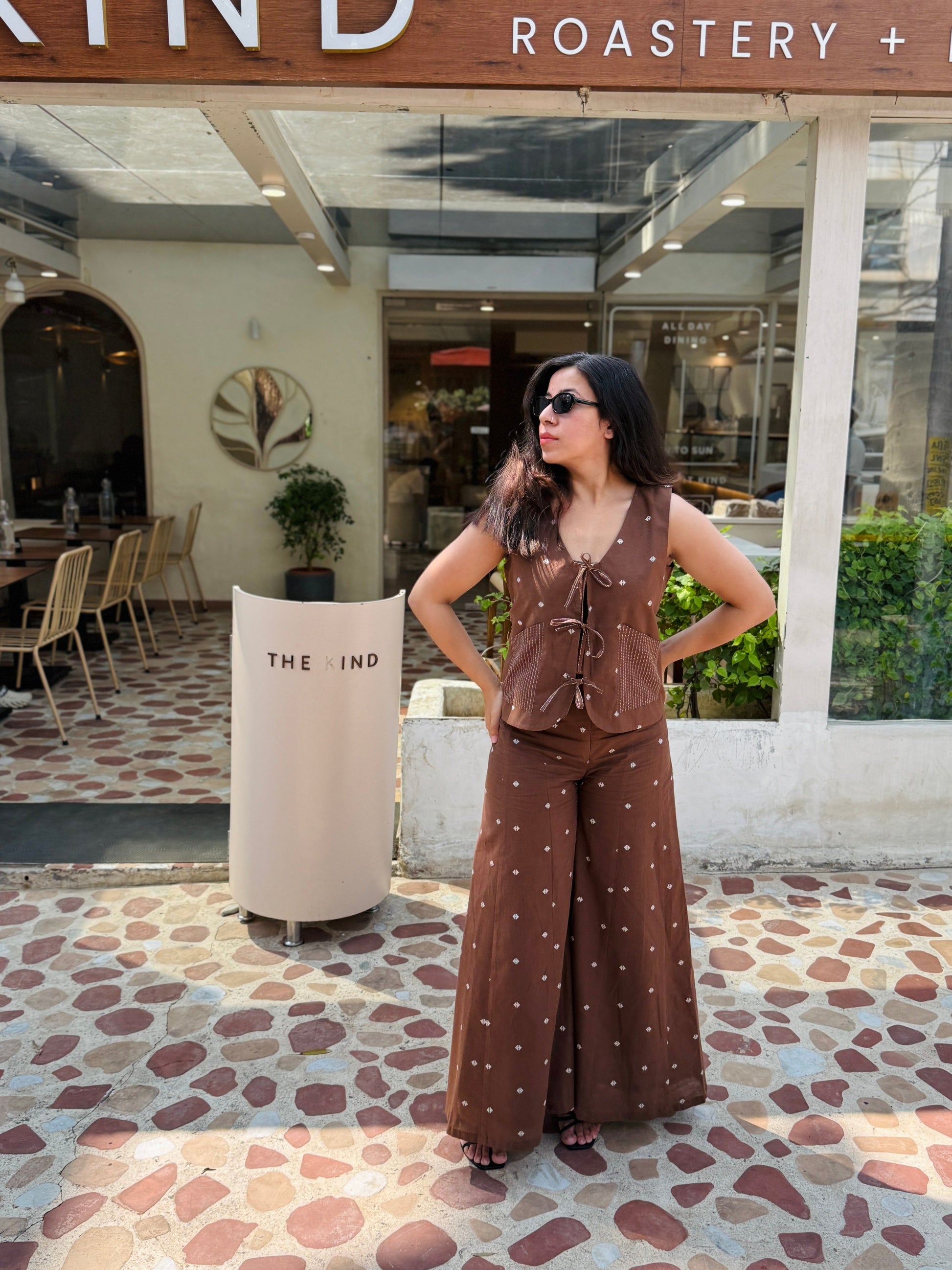 Woman in a brown outfit standing in front of 'The Kind Roastery + Brew' establishment.